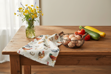 Load image into Gallery viewer, Chicken farmhouse kitchen towel folded on a wooden table with a mason jar of wildflowers, fresh produce, and a wire basket of brown and cream eggs."